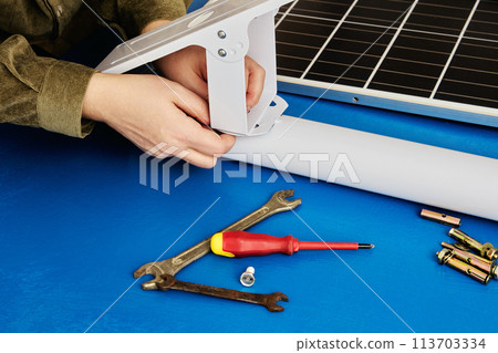 Homeowner assembles solar panel holder to use green technology on his property. 113703334