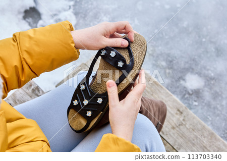 Anti-slip device for winter shoes, spikes on rubber backing, are put on sole to improve traction and prevent slipping in icy conditions. Anti-slip device for winter shoes, spikes on rubber backing, are put on sole to improve traction and prevent slipping in icy conditions. 113703340