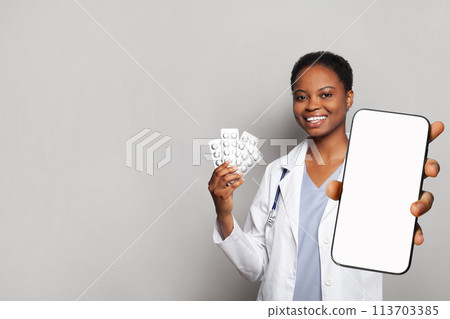 Positive doctor shows a phone with a blank display and pills. Online medical consultation  113703385