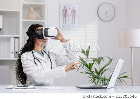A female doctor in white coat uses a virtual reality headset in a well-lit modern clinic office, demonstrating the integration of advanced technology in medical training and patient care. 113703546