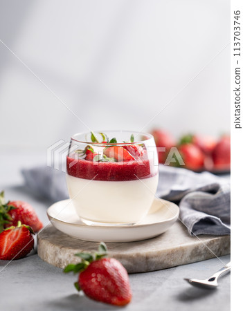 Panna cotta with strawberry and cream in glass with fresh berries on a marble board  113703746