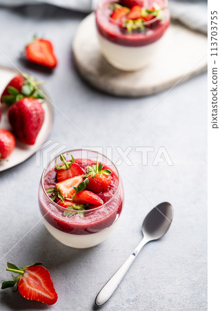 Strawberry and cream panna cotta in glasses with fresh berries on a light background. 113703755