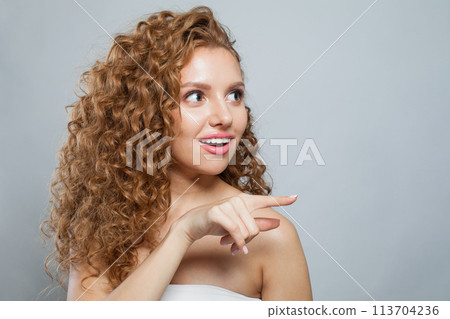 Shocked woman pointing finger. Beautiful female model with natural make-up, frizzy long hair  113704236