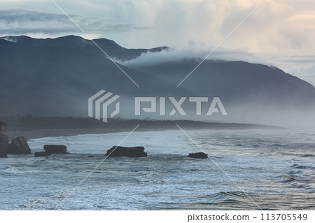 Ocean beach cliffs and mist in New Zealand 113705549
