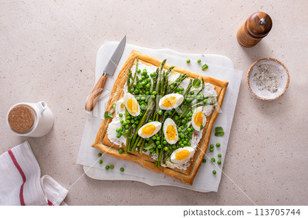 Fresh spring tart with green peas and asparagus on puff pastry Fresh spring tart with green peas and asparagus on puff pastry 113705744