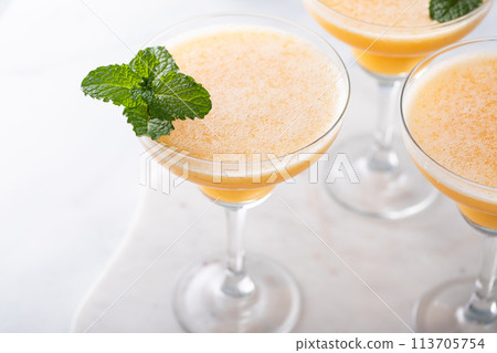 Frozen peach margaritas in three glasses with mint 113705754