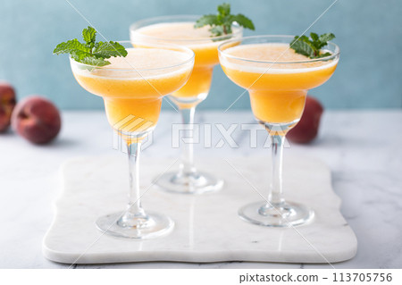 Frozen peach margaritas in three glasses with mint 113705756
