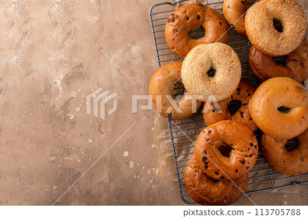 Variety of freshly baked bagels on a cooling rack Variety of freshly baked bagels on a cooling rack 113705788