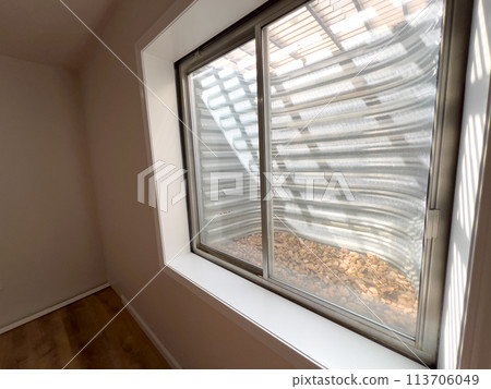 A single basement window in a family house casts natural light into a room undergoing remodeling, highlighting the new potential of the space. 113706049