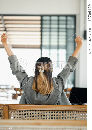 Businesswoman takes a moment to stretch and relax at her office workspace. Businesswoman takes a moment to stretch and relax at her office workspace. 113706199