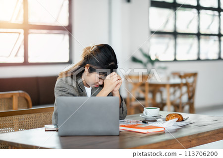 Stressed businesswoman at her laptop in a cafe with a furrowed brow, exhibiting signs of work-related stress. Stressed businesswoman at her laptop in a cafe with a furrowed brow, exhibiting signs of work-related stress. 113706200