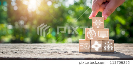 Hackathon concept, Hand holding wooden block on desk with brainstorm, development, programing, timing, teamwork and goal icon on virtual screen. 113706235