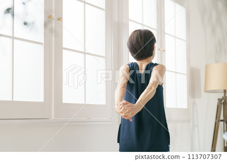一名30多歲的女性在窗邊伸懶腰 113707307