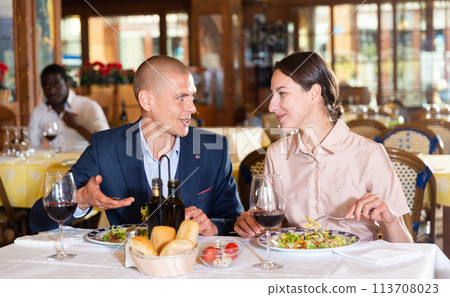 Loving smiling pair enjoying evening meal and conversation at restaurant Loving smiling pair enjoying evening meal and conversation at restaurant 113708023