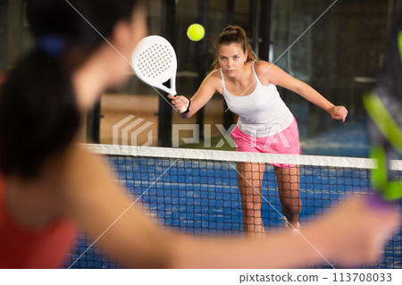 Concentrated energetic girl playing paddle tennis indoors 113708033