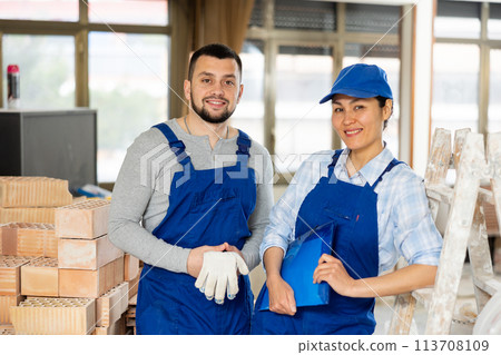 Woman and man builders posing at construction site indoors 113708109