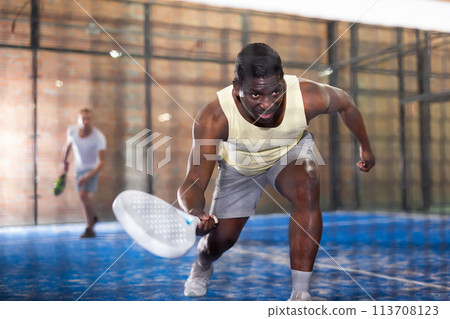 Sporty afro american man playing padel tennis indoor Sporty afro american man playing padel tennis indoor 113708123