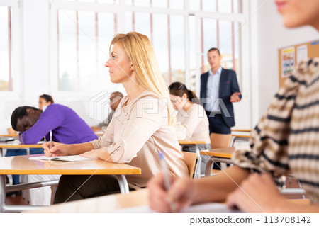 Focused blonde listening to lecture in classroom with group Focused blonde listening to lecture in classroom with group 113708142