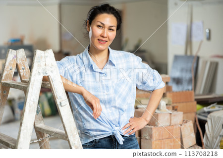 Portrait of satisfied asian woman against the backdrop of renovated room in cottage 113708218