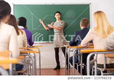 Asian female teacher lecturing to adult students in auditorium 113708219