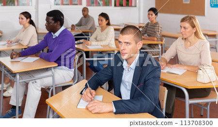 Attentive students at their desks in university auditorium Attentive students at their desks in university auditorium 113708300