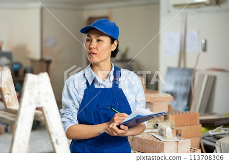 Female builder fills out documentation during repair work Female builder fills out documentation during repair work 113708306