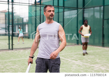 Young adult men playing doubles paddle tennis Young adult men playing doubles paddle tennis 113708314
