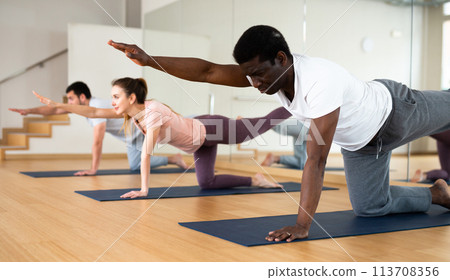 African american doing Dandayamna Bharmanasana during group yoga workout African american doing Dandayamna Bharmanasana during group yoga workout 113708356