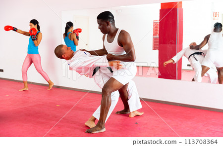 Men and woman exercising self-protection martial arts in gym 113708364