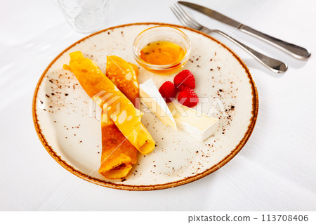 Sweet crepes with sliced soft brie, raspberries and honey 113708406