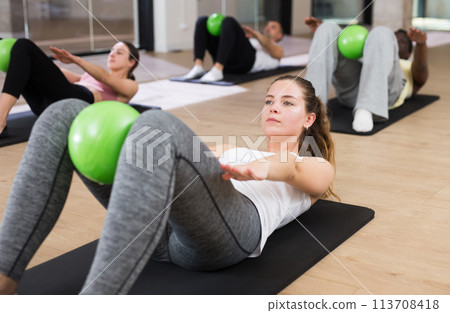 Young woman exercising with pilates ball during group class 113708418