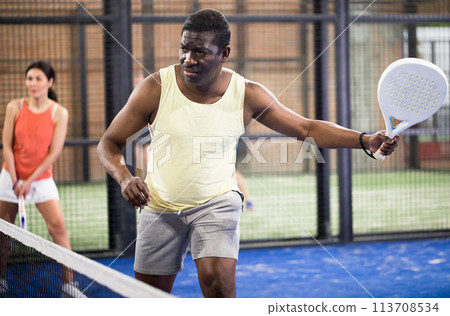 Sporty afro american man playing padel tennis indoor Sporty afro american man playing padel tennis indoor 113708534