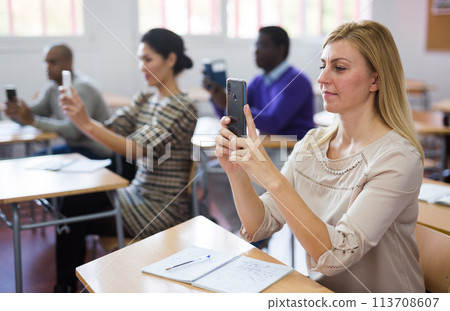 Female student using smartphone during lecture at adult education class Female student using smartphone during lecture at adult education class 113708607