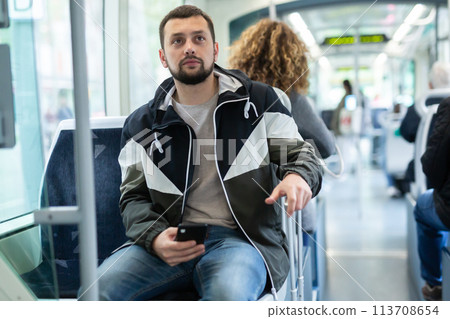 Male passenger in casual clothing talking on mobile phone in tram 113708654