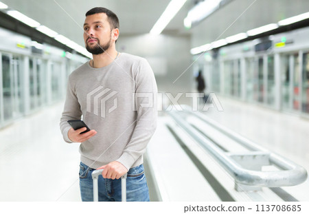 Man with luggage talking on mobile phone at the station in subway 113708685