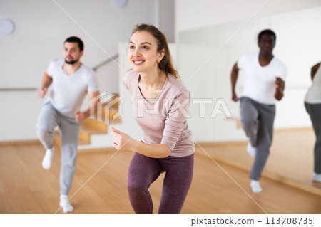Cheerful woman dancing aerobic dance during group training 113708735