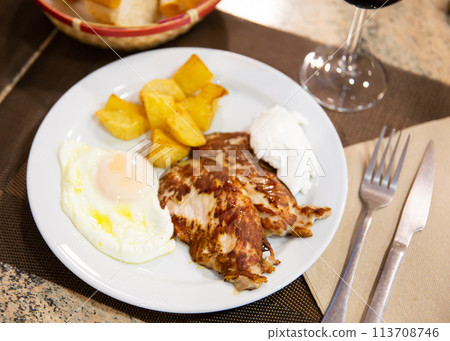 Traditional spanish fried pork with potato and egg on plate. Cerdo patata eggs Traditional spanish fried pork with potato and egg on plate. Cerdo patata eggs 113708746