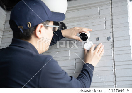 Male worker installing a security camera on a wall 113709649