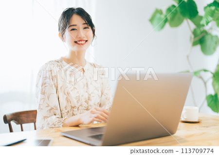 A woman using a personal computer at home 113709774