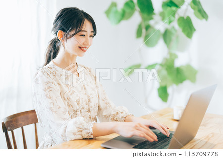 A woman using a personal computer at home 113709778