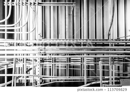 Looking up into an industrial ceiling with complex crisscross of utilities.  113709829