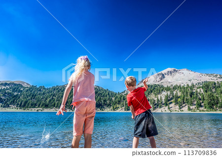 Children throwing rocks from the water's edge of Helen Lake in Lassen Volcanic National Park, California.  113709836