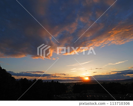 The sun setting over the shores of Lake Inawashiro, the orange clouds shining against the blue sky, is an impressive and beautiful sight. The sun setting over the shores of Lake Inawashiro, the orange clouds shining against the blue sky, is an impressive and beautiful sight. 113710306