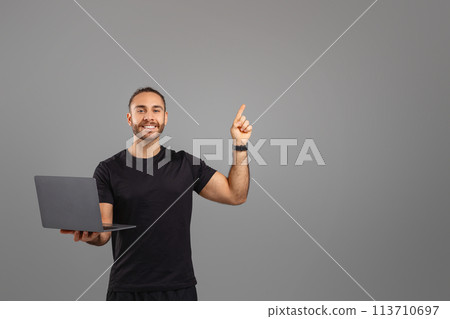 Man with a laptop pointing upwards at copy space 113710697