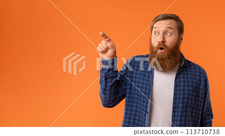 Amazed Redhaired Man Pointing Finger Aside At Empty Space, Studio 113710738