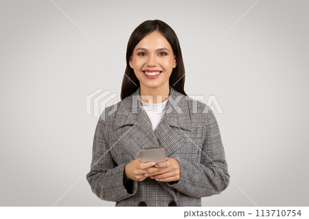 Content businesswoman texting on phone in chic blazer 113710754