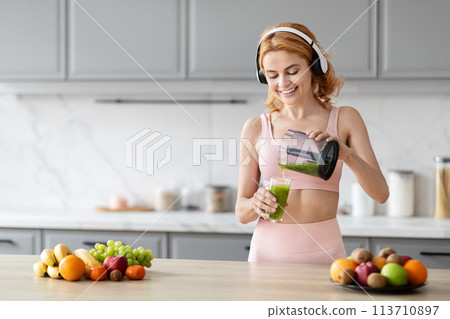 Woman pouring green smoothie in kitchen, copy space 113710897