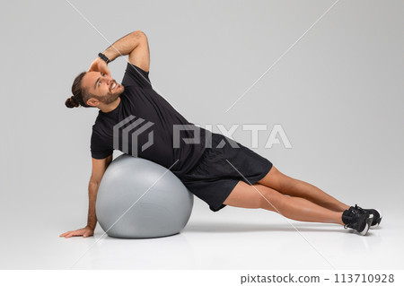 Man exercising with fitness ball in gym Man exercising with fitness ball in gym 113710928