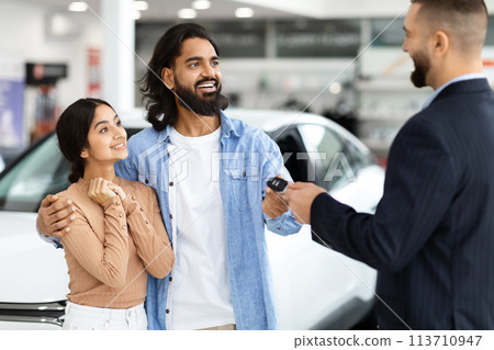 Car dealer handing keys to a happy indian couple 113710947