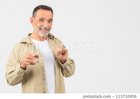 Senior man with pill and water practicing health care 113710956